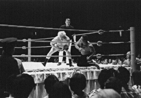 Rocky Montero works over Ray Stevens from outside the ring.